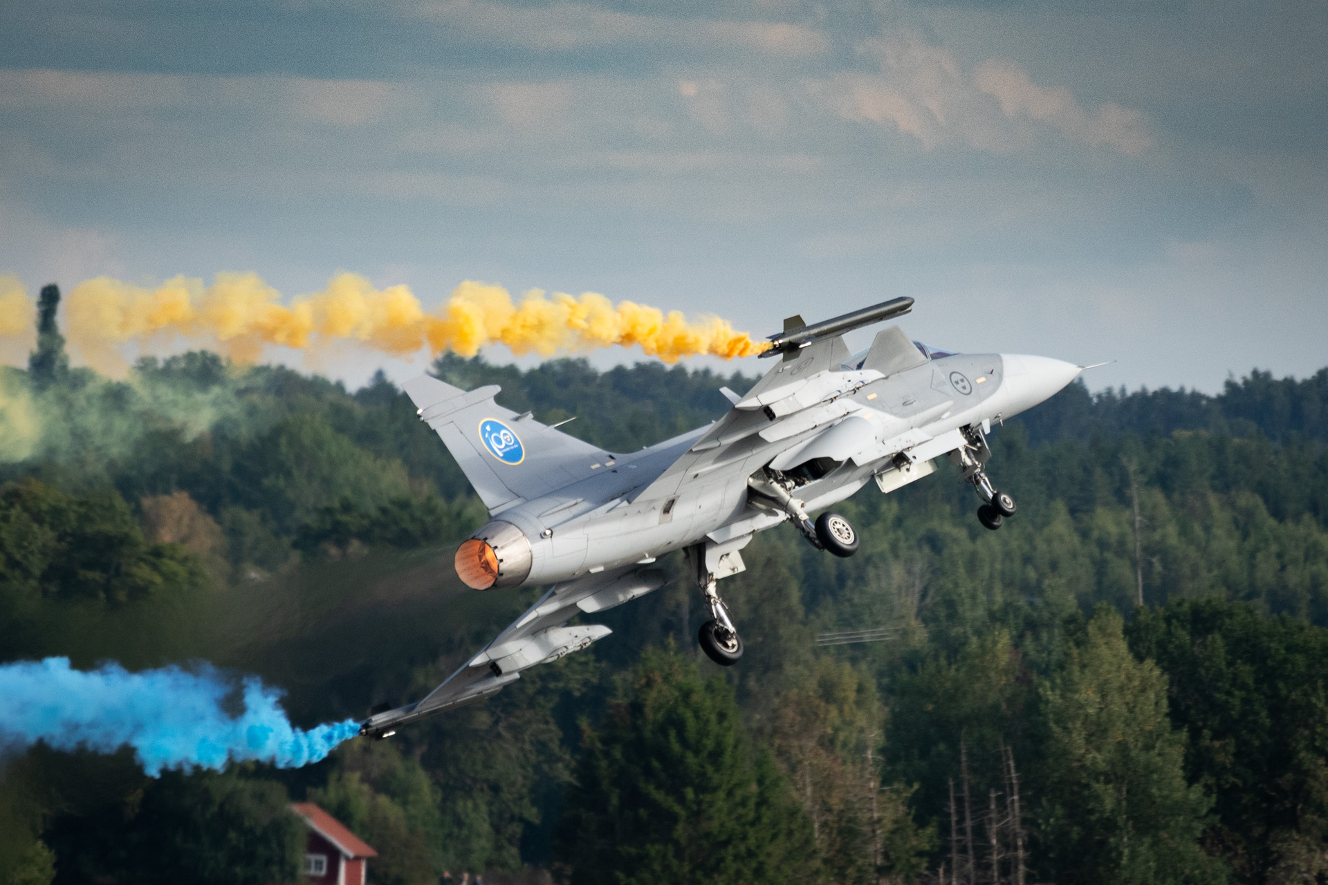 Gripen fighter aircraft banking through blue and yellow Sanders Smoke